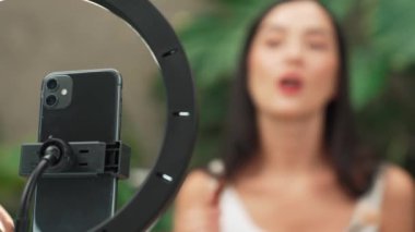 Telefon kamerasıyla odaklan güzel kadın içeriği yaratıcısı ya da arka planda güzellik blogcusu doğal bahçede kozmetik ve güzellik bakımı videosu yapıyor. Blithe