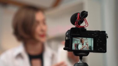 Kamera arkası görünümü gizli kadın etkileyicisi prim sosyal medya veya blog için canlı yayın vlog video gözden geçirme cilt çekim. Kozmetik stüdyosu ışıklandırmalı kız.