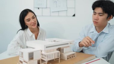 Profesyonel akıllı iş birliği mühendisi mühendis ekibi modern ofisteki ev yapısını planla kontrol ederken genç ve güzel proje yöneticisi not alıyor. Yaratıcı tasarım konsepti. Tertemiz...