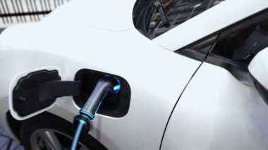 Akıllı telefon akü durumu arayüzünü elinde tutan iş kadını akıllı EV mobil uygulama ile otomobil parkındaki şarj istasyonundan elektrik şarj eden çevre dostu EV araba. İnceleyin