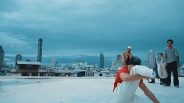 İspanyol hipster dansları şehrin mavi gökyüzü manzaralı çok kültürlü arkadaşlarıyla çevrili. Çatıda bir grup sokak dansçısı sahne alıyor. Aktif, eğlenceli, mutlu atmosfer. Açık hava sporu 2024 hiphop..