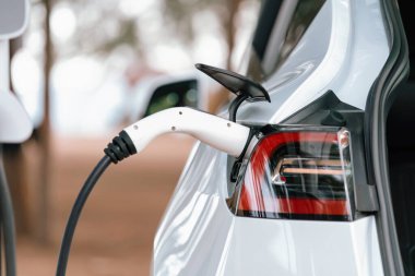Kapalı EV şarj kolu fişe takıldı veya elektrikli arabaya bağlandı, EV araba aküsünü temiz çevre için sıfır CO2 emisyonu ile alternatif ve sürdürülebilir enerjiyle şarj etti. Kalıcı
