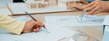 Profesyonel mimar takımı sürdürülebilir ev malzemelerini seçerken, yetenekli mühendis de ev modeli ve renk paletini kullanarak toplantı masasına yerleştirir. - Yakın çekim. Değiştirilmiş.