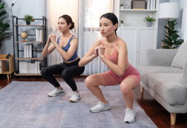 Egzersiz arkadaşı ya da antrenörü olan enerjik bir kadın evde egzersiz yapıyor. Genç atletik Asyalı kadın dayanıklılığı ve dayanıklılık antrenmanı..