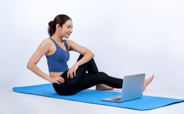 İnternetteki videodan alınan talimatlara göre spor kıyafeti giymiş genç Asyalı bir kadın spor egzersizinden önce geriniyor. Sağlıklı atletik bir kadınla vücut egzersizi izole bir zeminde ısınıyor. Kuvvetli