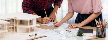 Akıllı mimar mühendis ve iç mimar birlikte çalışıyor ve ev modelini ölçmek için plan ve mimari ekipmanlarla toplantı masasında cetvel kullanıyor. Takım çalışması konsepti. Filizlenen.