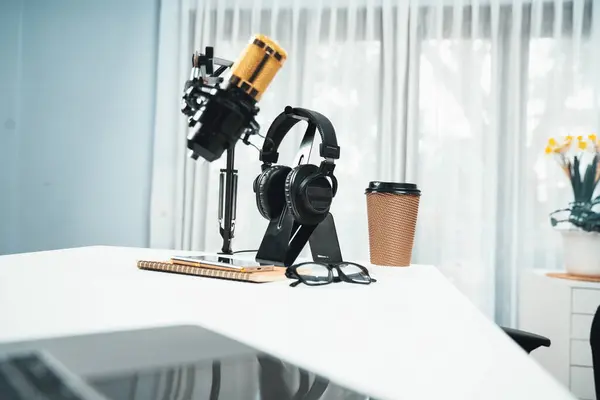 All stuff sets of live streaming standing on white desk consist of microphone, headsets, coffee cup, smartphone, glasses and notebook. Concept of equipment for coaching host channel. Tastemaker.