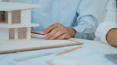 Profesyonel erkek mühendis ev modelini cetvel kullanarak ölçerken güzel bir kooperatif iş arkadaşı verileri analiz etmek için dizüstü bilgisayar kullanarak birlikte çalışıyor. Yaratıcı tasarım ve takım çalışması. - Yakın çekim. Tertemiz..
