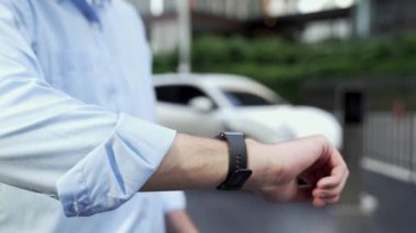 İş adamı, istasyonun otoparkından şarj olurken akıllı telefon hologramındaki EV aküsünün durumunu kontrol ediyor. EV teknolojisi adaptasyonu için temiz enerjinin gelecekteki yaşam tarzı. İnceleyin