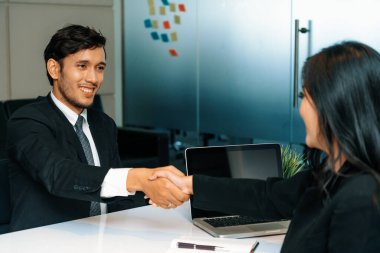 İş adamları konsepti kabul ediyor. İş adamı ve Asyalı iş kadını ofiste el sıkışırlar. uds