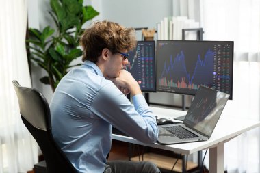 Piyasa stoku veri yatırımlarında dizüstü bilgisayara odaklanarak ekranlarda gerçek zamanlı dizüstü bilgisayar üzerinde çalışan genç bir tüccar. Modern ofiste, dinamik para bozdurma oranını analiz ediyorum. Toplayıcı.