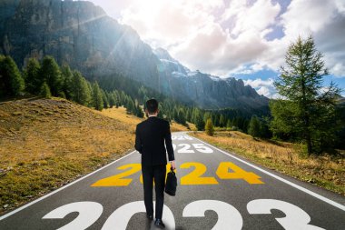 2024 yılbaşı yolculuğu ve gelecek vizyon konsepti. 2024 'ün başında mutlu bir yeni yıl kutlaması için otoyolda ilerleyen iş adamı mutlu ve başarılı bir başlangıç yapacak. .