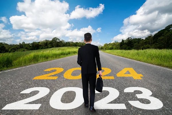 2024 New Year journey and future vision concept . Businessman traveling on highway road leading forward to happy new year celebration in beginning of 2024 for bliss and successful start .