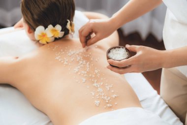 Lüks spa salonlarında sıcak mum ışığında cilt bakımı yaptıran kadın müşteri. Sağlık Spa vücut fırçasında tuz temizleme güzellik tedavisi. Sessiz.