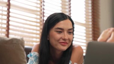 Kanepede yatan genç bir kadın internet bankacılığı için kredi kartıyla dizüstü bilgisayar kullanıyor. Evdeki online ödeme kapısından alışveriş yapıyor. Modern ve uygun online satın alma. Blithe