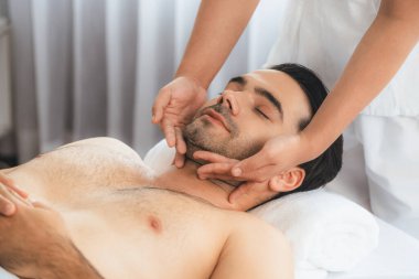 Beyaz adam stres önleyici kafa masajından ve lüks bir tatil beldesi veya otel spa salonundaki modern ışık ortamında yüz güzelliği eğlencelerini şımartmaktan hoşlanıyor. Sessiz.