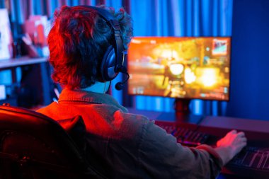Genç oyun flamasının sunucu kanalı, takım oyuncusu, dijital neon odasında mikrofonlu kulaklık takarak bilgisayar ekranında çoklu oyuncuyla savaş oyunu oynuyor. Toplayıcı.