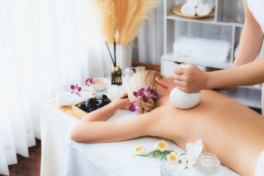 Sıcak bitkisel top spa masaj vücut tedavisi, masör kadın vücuduna nazikçe şifalı bitki torbası bastırıyor. Aromaterapi dinlenme sükuneti ve sükuneti kaplıca salonundaki atmosferi aydınlatıyor. Sessiz.