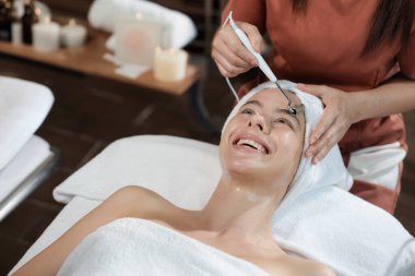 Güzeller güzeli beyaz kadın güzellik teçhizatı ve tıbbi ekipmanlarla çevrili modern kaplıca salonundaki profesyonel eller tarafından masaj yaptırırken spa yatağında uzanıyor. Kapatın. Huzur