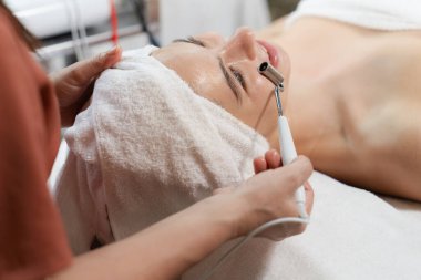 Güzeller güzeli beyaz kadın güzellik teçhizatı ve tıbbi ekipmanlarla çevrili modern kaplıca salonundaki profesyonel eller tarafından masaj yaptırırken spa yatağında uzanıyor. Kapatın. Huzur