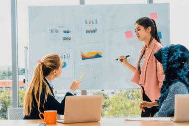 Çok kültürlü çalışma grubu. Farklı etnik kökenden iş kadınları, Kafkasyalı, Asyalı ve Araplardan oluşan bir ekip ofiste dizüstü bilgisayarla birlikte çalışıyor. Çok ırklı takım çalışması konsepti. uds