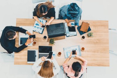 Modern ofisteki iş adamları ve iş kadınlarıyla grup toplantısındaki iş adamlarının en üst düzey görüşü, masada dizüstü bilgisayar, kahve ve belge ile. Kurumsal şirketler uds