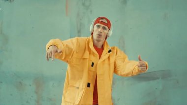 Beyaz hipster sokak, şehir merkezinde ayak sesleri gösteriyor ya da pratik yapıyor. Break dansçı, kulaklıktan müzik dinlerken hip-hop müziğine adım atıyor. Açık hava sporu 2024. Gri arka plan. hiphop.