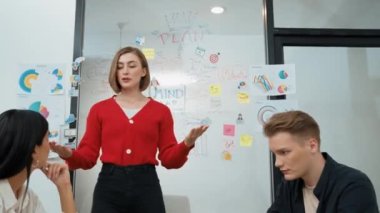 Yetenekli genç ve güzel iş kadını, yaratıcı iş toplantısında yakışıklı yönetici dinlerken zihin haritalama ve istatistiksel grafik kullanarak pazarlama fikrini kendine güvenle sunuyor. Tertemiz..