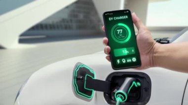 Akıllı telefon uygulaması ekranda dijital EV araba aküsünün şarj istasyonu ile şarj olurken durumunu gösteriyor. Otomobil kullanımı kavramı için alternatif sürdürülebilir ve temiz enerji. İnceleyin