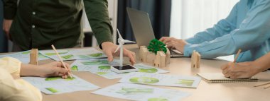 Yenilenebilir enerji ve eko kenti temsil eden ahşap bloğu temsil eden yel değirmeni modeli, çevreci dökümanların dağıtıldığı yeşil iş toplantısı masasına yerleştirildi. Ön manzara. Tanımlama.