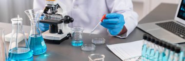 Bilimadamları tıbbi laboratuvarda kimyasal deneyler yapıyor. Aşı ilacı veya antibiyotik gelişimi için pipetten deney tüpüne kesin miktarda sıvı bırakıyor. Neoterik