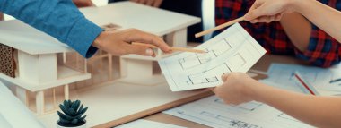 Mimari takım analizi ve ev modeli, plan ve mimari ekipmanlarla toplantı masasında ev inşaatı hakkında beyin fırtınası. Yaratıcı tasarım ve takım çalışması. Filizlenen.