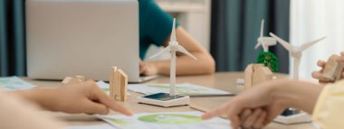 Yel değirmeni modeli, ahşap blok ve çevresel dökümanların etrafa saçıldığı yeşil işletmelerin sunumu sırasında yenilenebilir enerji kullanılarak temsil ediliyor. - Yakın çekim. Tanımlama.