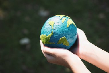 Dünya gezegenini ESG ilkesi ve çevre dostu enerjisiyle daha parlak bir gelecek için Dünya günü olarak el ele tutuşan genç çocuklar. Döngü