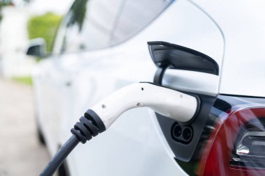 Elektrikli araç portuna bağlı EV şarj prizi kolu şarj istasyonundan şarj oluyor. Modern tasarlanmış EV araba ve daha iyi bir gelecek konsepti için temiz enerji sürdürülebilirliği. Eşzamanlama
