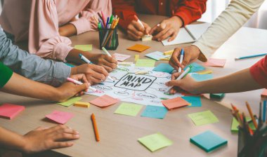 Yaratıcı iş adamları, zihin haritalama kullanarak pazarlama stratejisi ve iş planı hakkında beyin fırtınası yapıyorlar. Girişim ekibi kağıda yazmak için birlikte çalışır. Eline odaklan. - Yakın çekim. Değiştirilmiş.