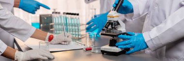 Kendini adamış bir grup bilim adamı yeni bir aşı ilacı ya da antibiyotik geliştirmek için tıbbi laboratuvarda mikroskop kullanarak kimyasal deney yapıyorlar. Biyoteknoloji laboratuvarı ve tıp araştırma konsepti. Neoterik