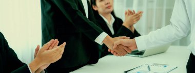 Toplantı masasında iş adamları el sıkışır. İş görüşmesi başarılı mı yoksa başarılı bir konuşma anlaşması mı?