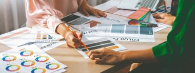 Profesyonel iç mimarların kırpılmış görüntüsü proje masasında renk paleti dağılımı ile ana tema rengini tartışır ve beyin fırtınası yapar. Yaratıcı iç tasarım konsepti. Değiştirilmiş.