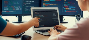 Bilgisayar ekranında program kodu gösterilirken iki akıllı kooperatif bilgisayar mühendisi program kodunu çözmek için takım çalışması yapıyor. Laptop, web geliştirme, programcı, Java betiği. Filizlenen.