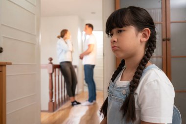 Stresli ve mutsuz genç kız arka planda ebeveynleri tartışırken köşede ağlayıp üzülüyor. Evde aile içi şiddet ve travmatik çocukluk depresyona dönüşür. Eşzamanlama