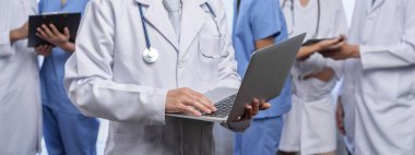 Hastanede dizüstü bilgisayar ve tabletle birlikte çalışan doktor hemşire ve sağlık uzmanlarına sahip tıbbi personel ekibi. Panoramik pankartta tıbbi işyeri ve sağlık hizmetleri topluluğu. Neoterik