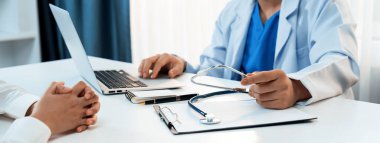 Klinikteki ya da hastane ofisindeki doktor randevusuna katılan hasta, tıbbi tedavi seçeneklerini tartışıyor ve muayene sonuçlarını ya da hastalıkla ilgili tıbbi kayıtları açıklıyor. Panorama Katı