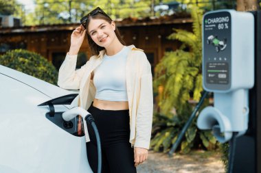 Genç kadın ve sürdürülebilir kentsel yol, bahar bahçesi, yeşil şehir sürdürülebilirliği ve çevre dostu EV arabadaki açık kafede çalışan EV elektrikli araba. Yararlı