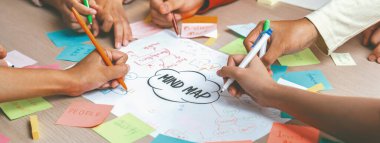 Profesyonel başlangıç grubu zihin haritası kullanarak yaratıcı pazarlama fikrini paylaşıyor. Genç yetenekli iş adamları yapışkan notlar yazarken beyin fırtınası planı yapıyorlar. Eline odaklan. - Yakın çekim. Değiştirilmiş.