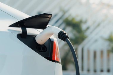 Kapalı el, şehrin park alanındaki şarj istasyonundan elektrikli araba aküsünü şarj etmek için EV şarj aleti yerleştirdi. Sürdürülebilir çevre dostu şehir yolculuğu için şarj edilebilir EV araba. Yararlı