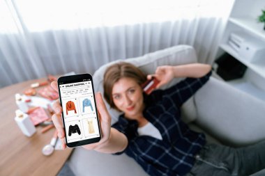 Genç mutlu kadın internetten alışveriş yaparak ürün satın alırken aynı zamanda internet üzerinden online ödeme sistemi ile çevrimiçi mağaza platformundan en yüksek siber güvenlik tarafından korunan ürünler sipariş ediyor.