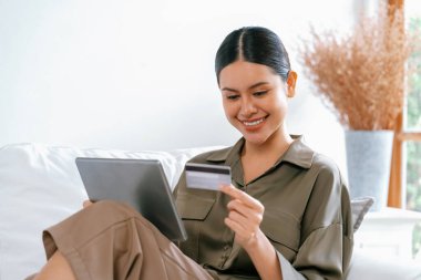 Genç mutlu Asyalı kadın internetten alışveriş yaparak ürün satın alırken aynı zamanda internetten kredi kartıyla online ödemeler sipariş ederek çevrimiçi mağaza platformundan en yüksek sanal güvenlik tarafından korunuyor.