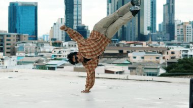 Profesyonel İspanyol break dansçısı B boy dansı yaparken çatıda şehir manzaralı, şehirli çok kültürlü arkadaşlar var. Genç modern dans grubu hip hop hareketi yapıyor. Açık hava sporu 2024. ÇalışmaComment.