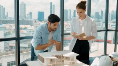 Beyaz mimar mühendis takımı ev modelini ölçmek için birlikte çalışıyor. Genç, güzel tasarımcı ev inşaatı yazarken erkek işçiler mimari modelleri inceliyor, inceliyor, inceliyor. Tartışma